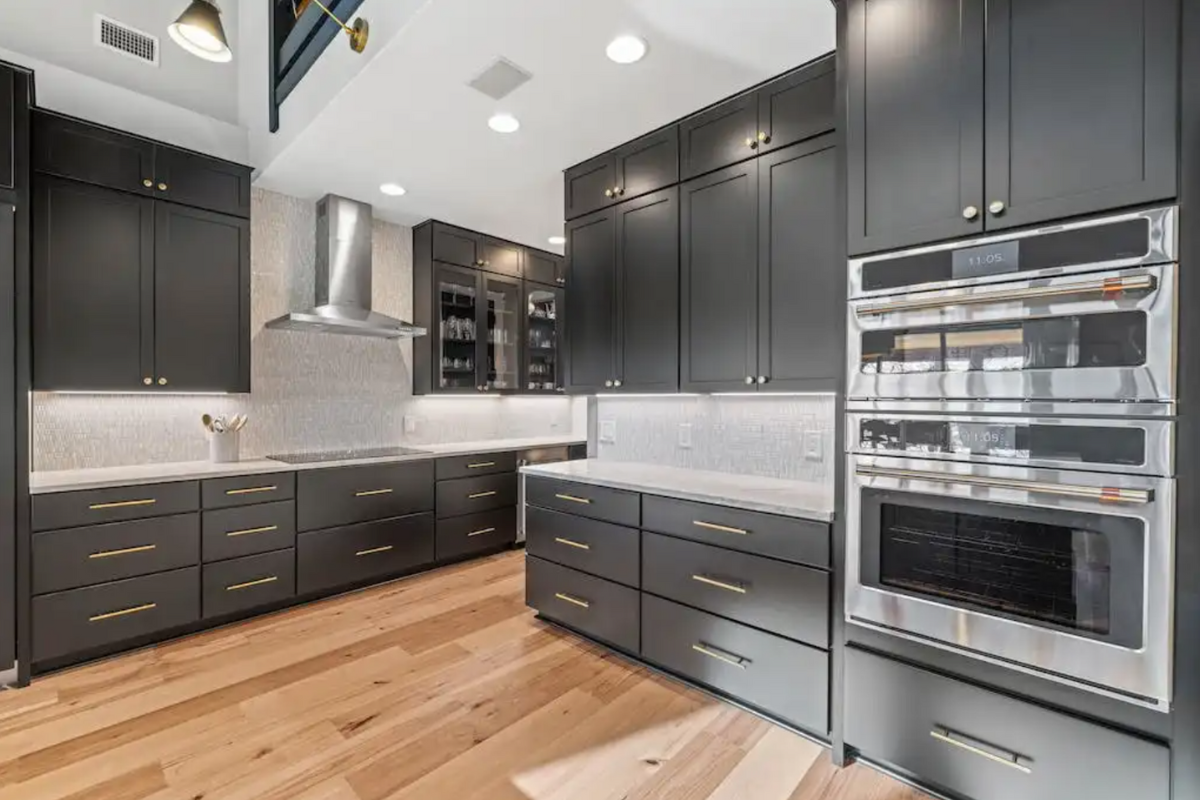 Modern black shaker kitchen cabinets with stainless steel appliances and rustic light wood floors