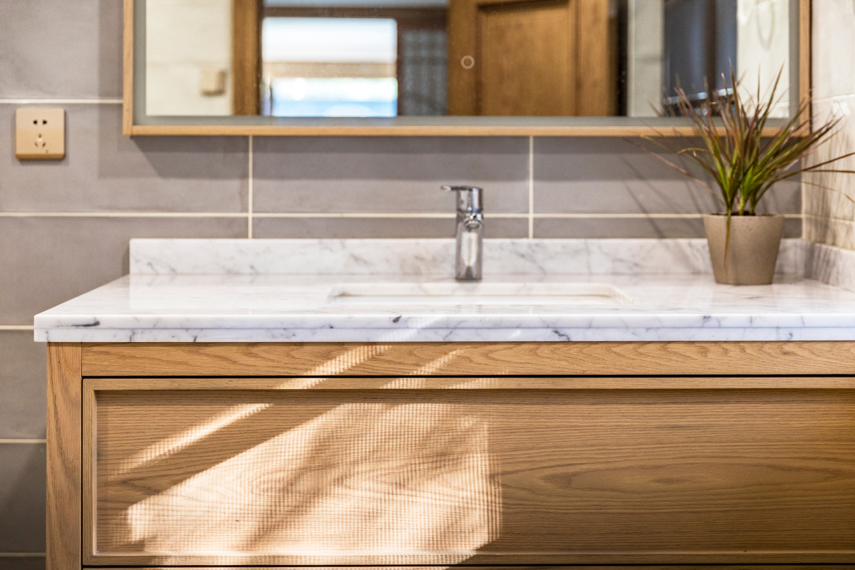 Close-up of an inset wood vanity cabinet with a thin marble countertop