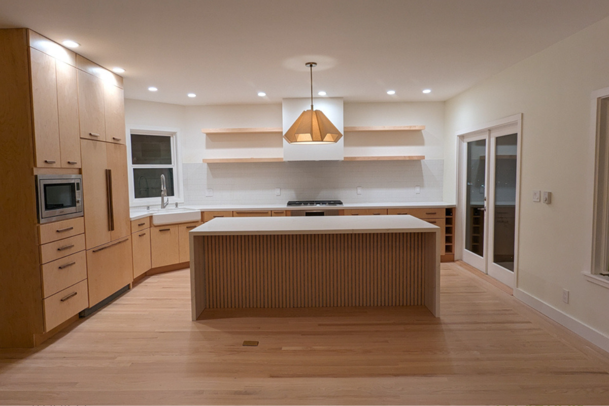 L-shaped slab kitchen design in light wood cabinets with white countertops and contemporary style