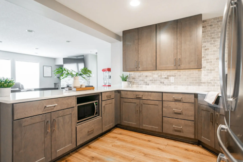 U-shaped basement bar with dark brown kitchen cabinets and brushed nickel cabinet pulls