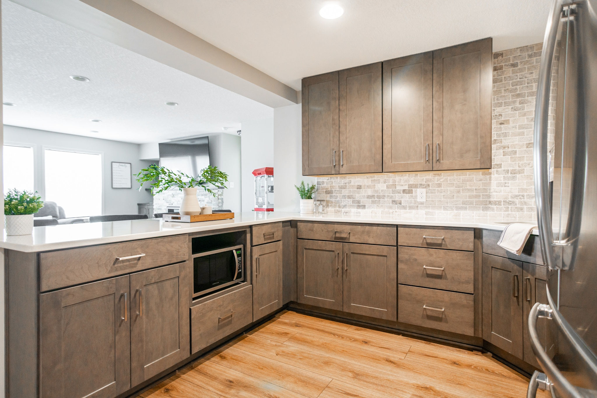 CliqStudios project: Warm wood shaker kitchen cabinets in a basement bar with tile backsplash