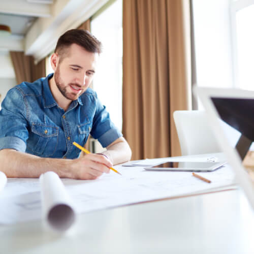 Kitchen designer hand-drafting floor plans on a desk