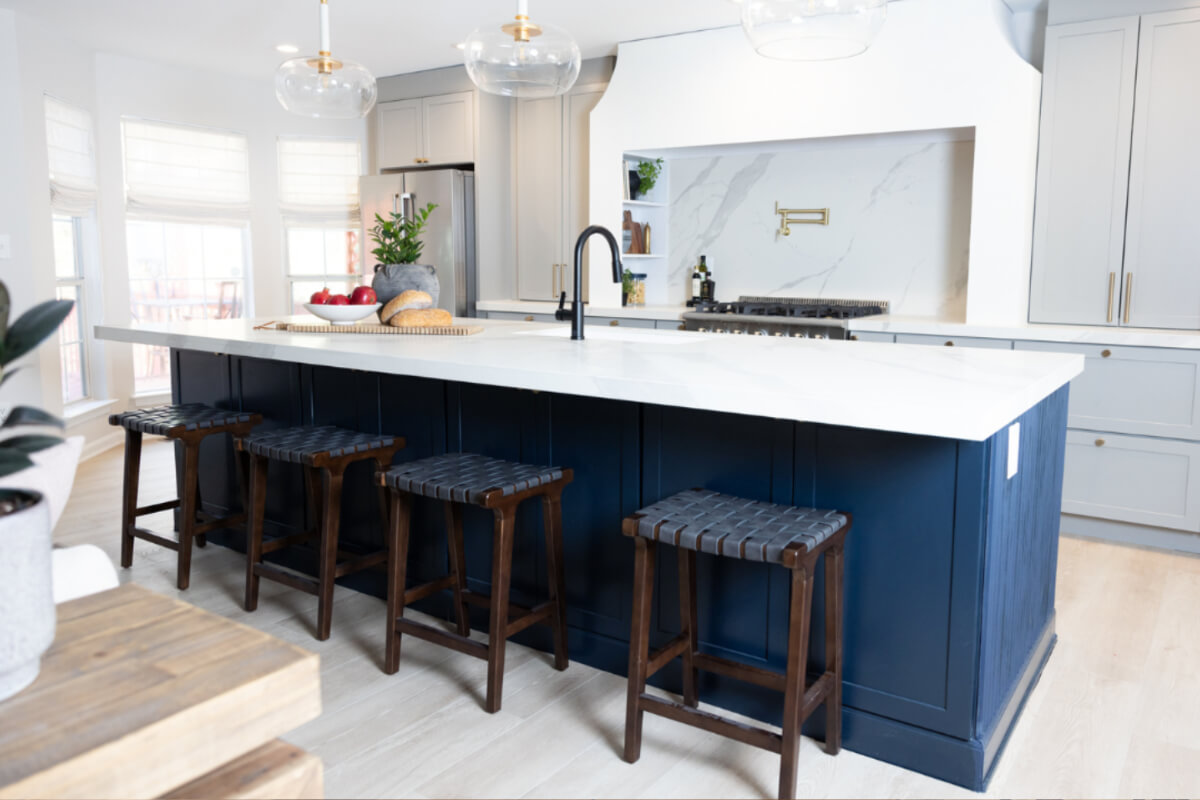 Light gray shaker kitchen design with large navy blue island and white countertops