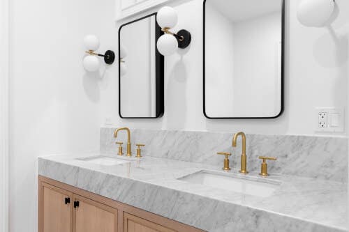 Light wood inset vanity cabinets with thick marble countertops