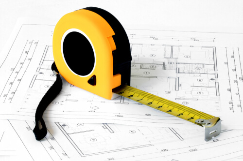 Yellow measuring tape sitting on top of home blueprints