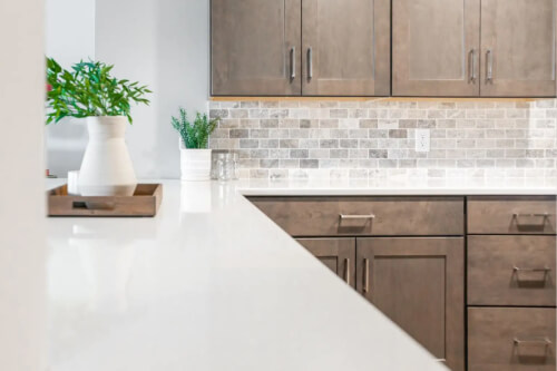 Medium-brown shaker kitchen cabinets with brushed nickel pulls and white quartz countertops