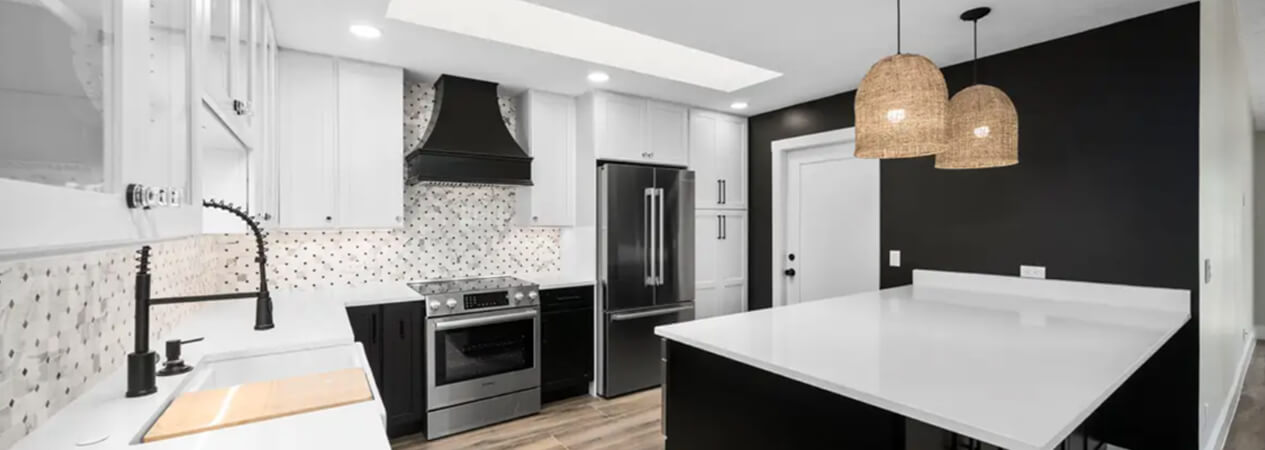 L-shaped kitchen with black shaker base and island cabinets with white shaker wall cabinets and white quartz countertops