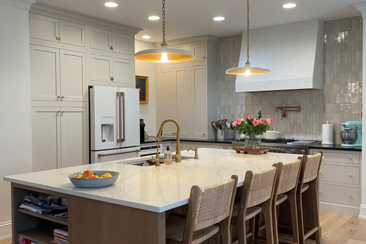 Large inset kitchen design in cream paint with a light wood stained island and white quartz countertops