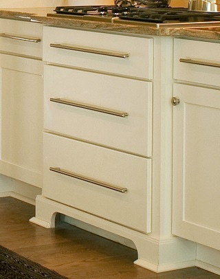 cream-colored cabinet drawer unit bumped out with furniture-look feet supports cooktop