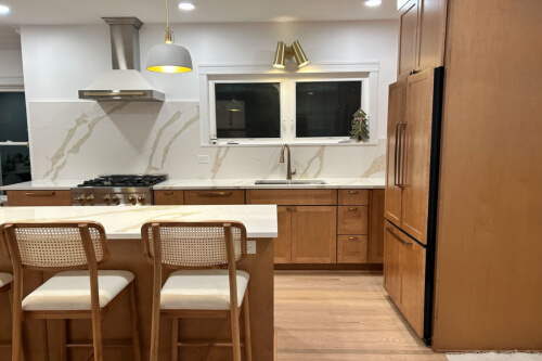 L-shaped light maple cabinet kitchen with island and matching slab quartz backplash