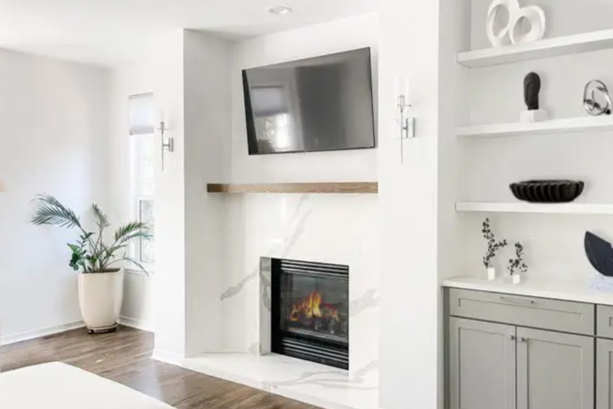 Large white marble fireplace with shaker gray entertainment center cabinets and floating shelves on the right side