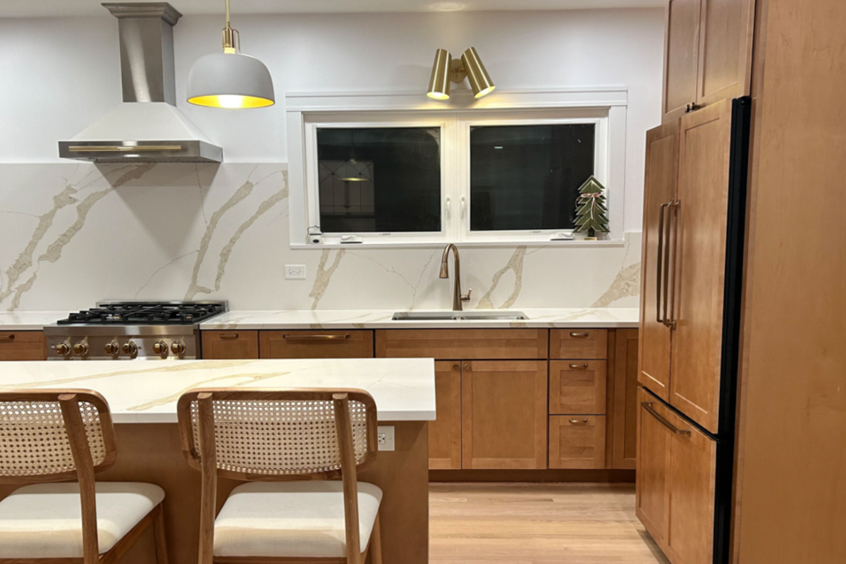 Upscale medium wood kitchen cabinets in shaker style with matching quartz countertops and slab backsplash