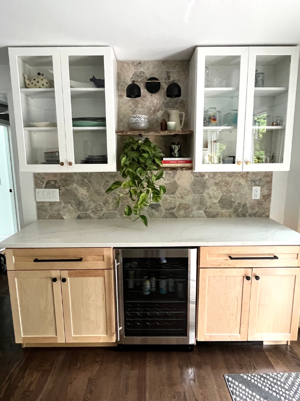 Beverage bar wall with white shaker glass wall cabinets with natural wood shaker base cabinets, white quartz countertops, and a hex-shaped stone tile backsplash Beverage bar wall with white shaker glass wall cabinets with natural wood shaker base cabinets, white quartz countertops, and a hex-shaped stone tile backsplash
