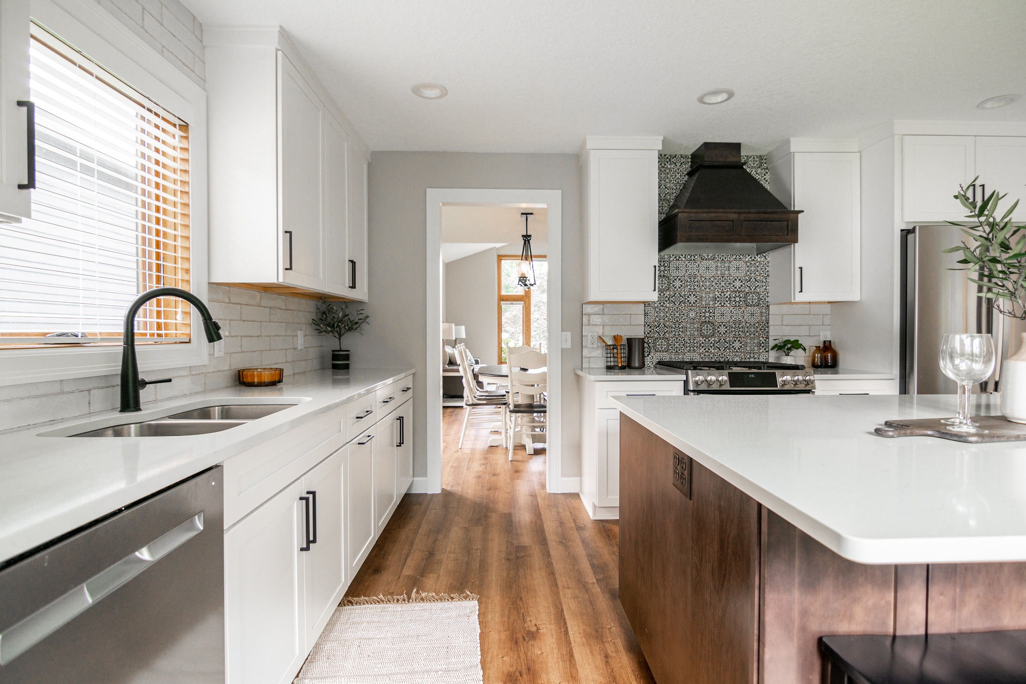 CliqStudios project: White shaker kitchen cabinetry with dark wood stained island and wood kitchen hood