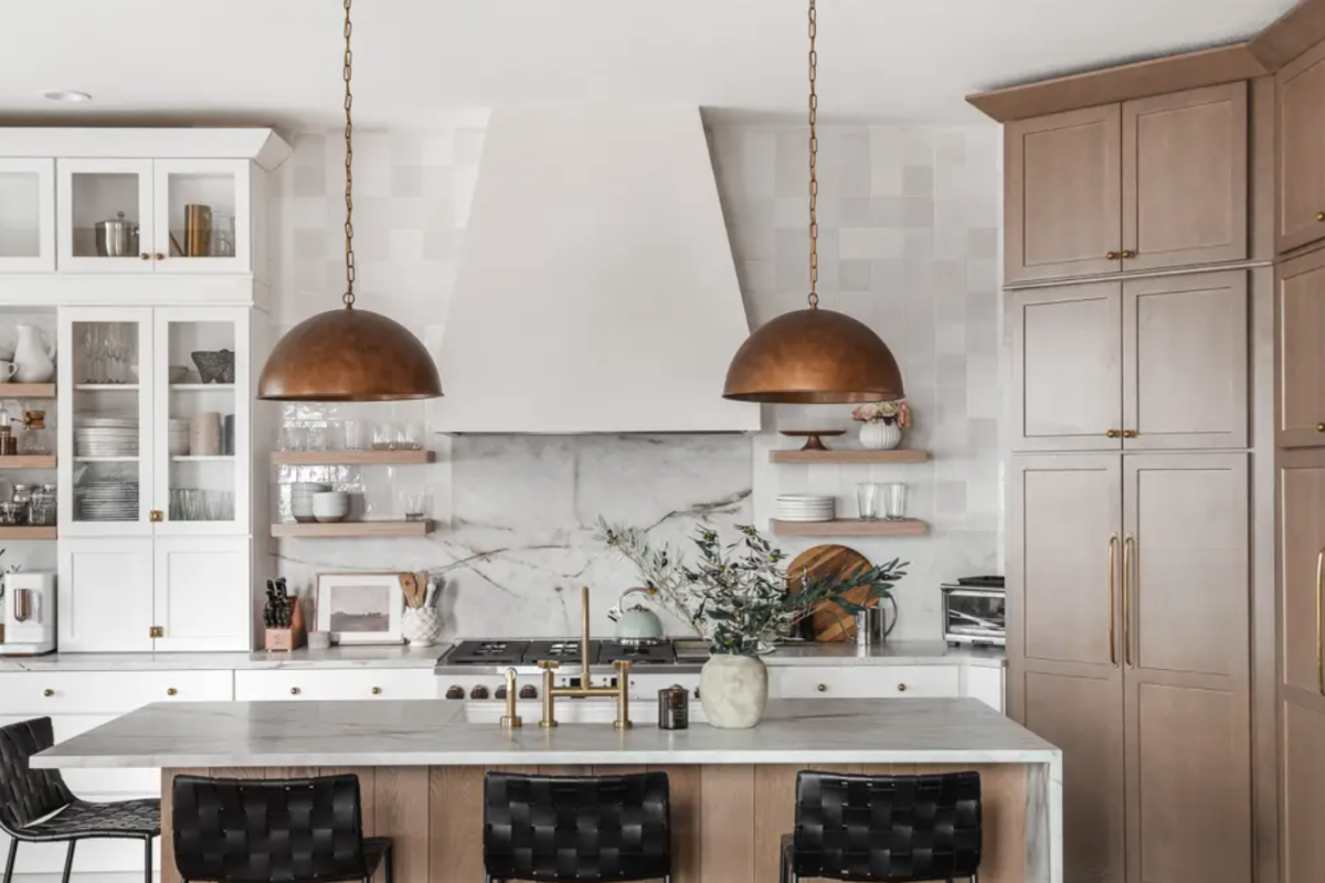 Two-tone white and light wood kitchen design with a plaster hood and copper accents