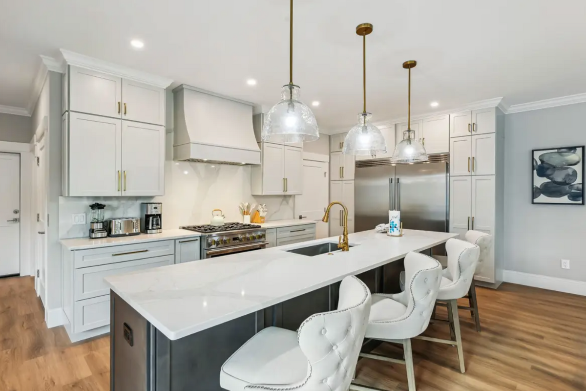 Light gray stacked shaker kitchen design with dark gray stained island and white countertops