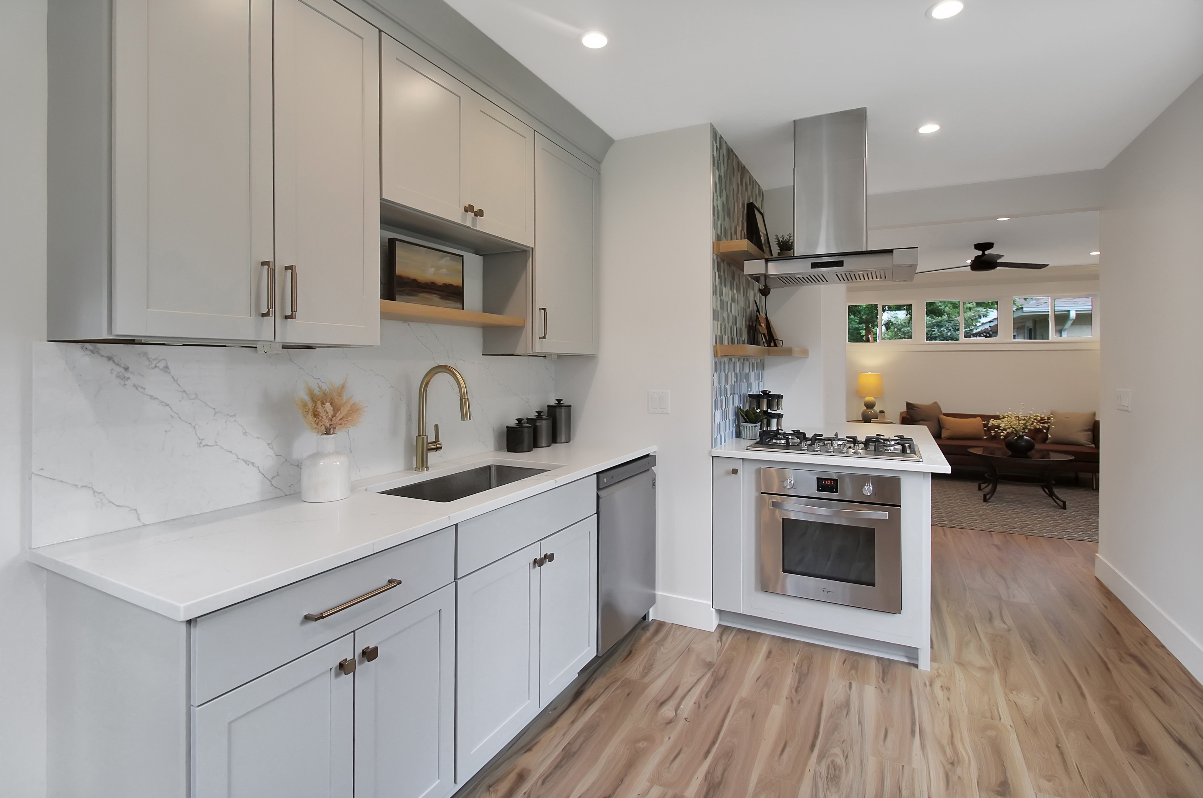 CliqStudios project: Light gray, one-wall shaker kitchen cabinets with brass hardware, and marble slab backsplash