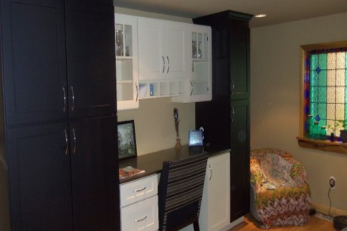 Built-in home office desk cabinets with black shaker pantries flanking white shaker drawer bases and mullion glass door wall cabinets