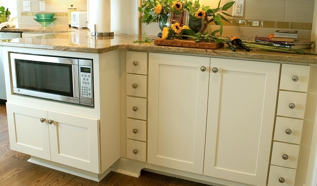 under-counter microwave and spice drawers in white kitchen cabinets