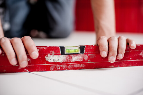 Person using a red level on tile floors