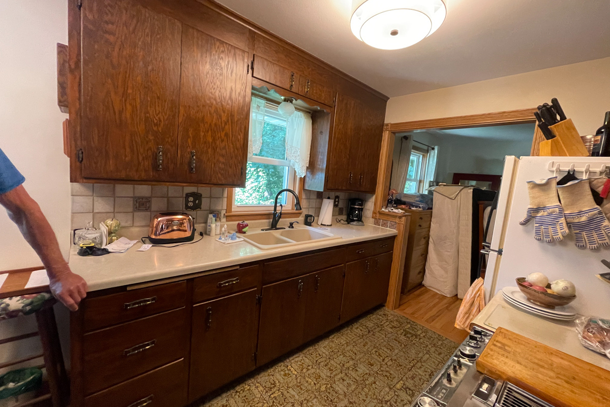 Dark and outdated oak cabinets with old aged vinyl flooring and laminate countertops