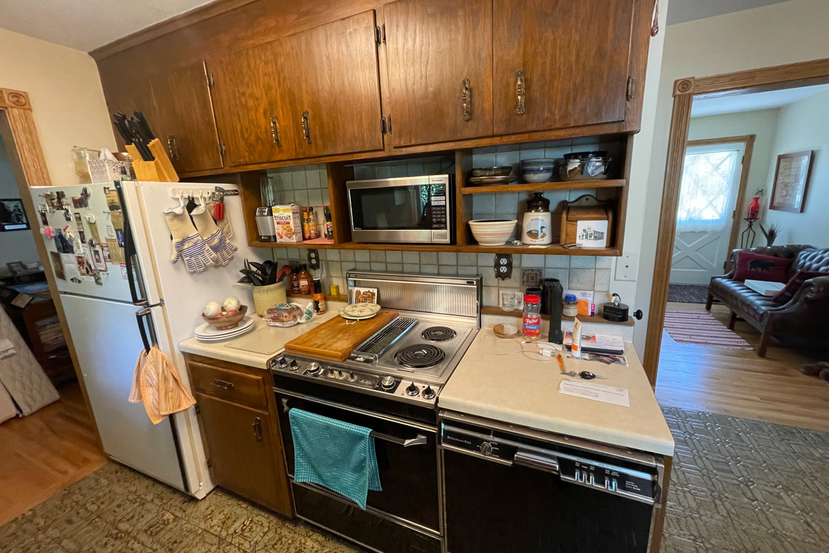 Dark and outdated oak cabinets with old aged vinyl flooring and laminate countertops