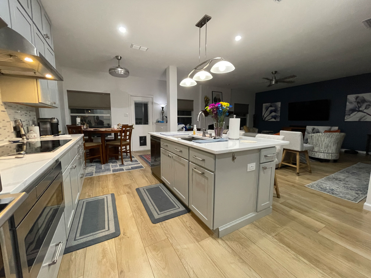 Light gray stacked shaker kitchen cabinets and island with white quartz countertops, brushed nickel cabinet hardware and modern pendant lighting