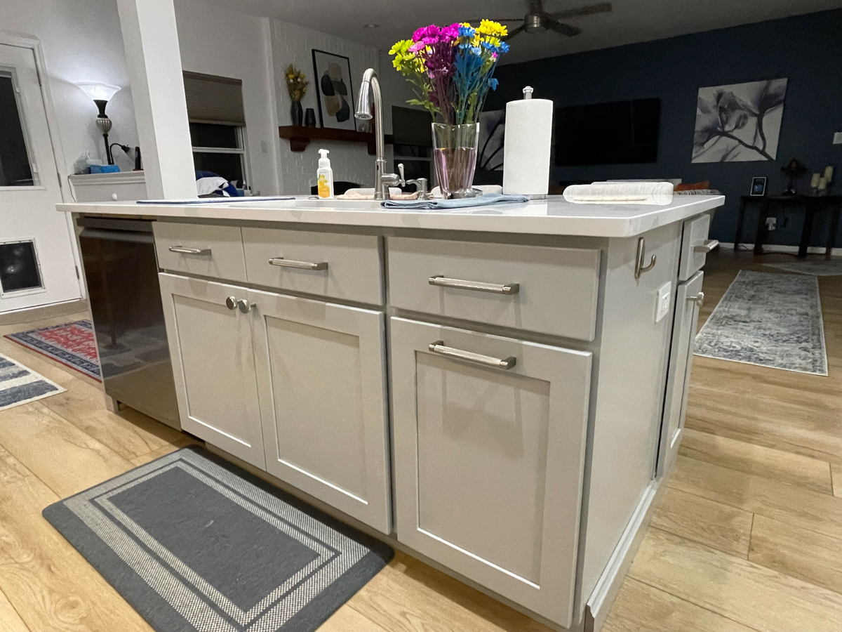 Light gray stacked shaker kitchen cabinets and island with white quartz countertops, brushed nickel cabinet hardware and modern pendant lighting