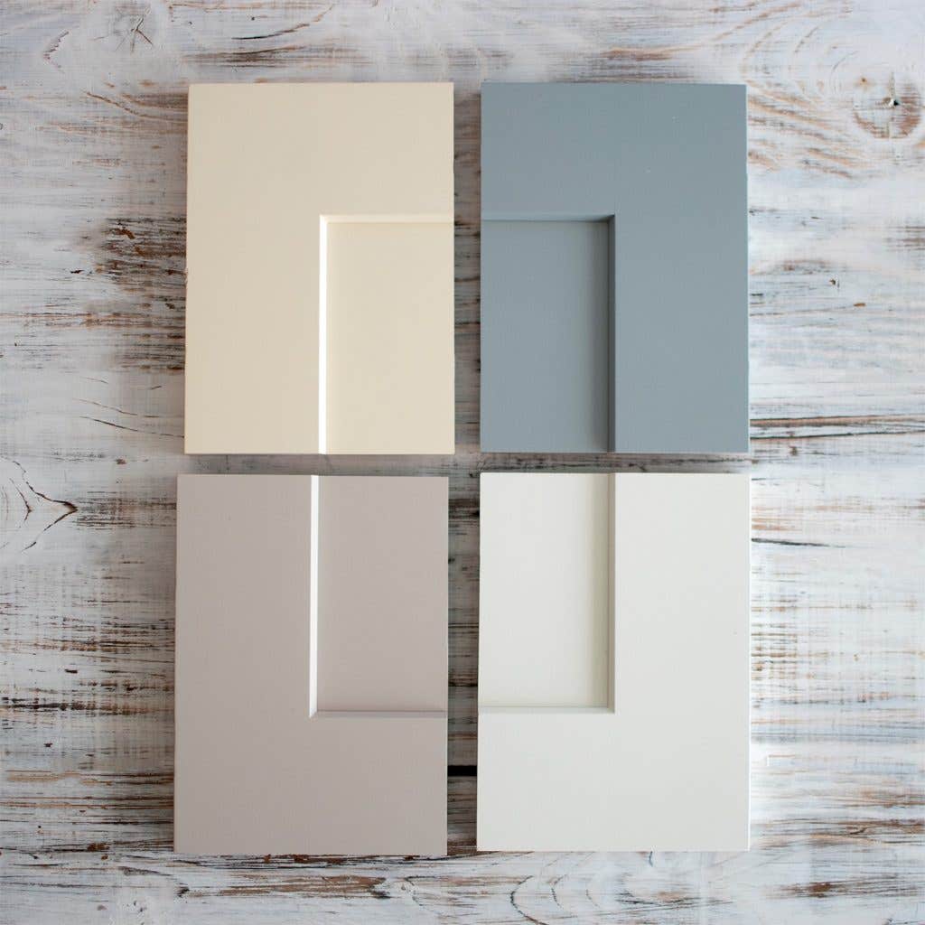 Four shaker cabinet door samples in cream, blue-gray, light gray, and white