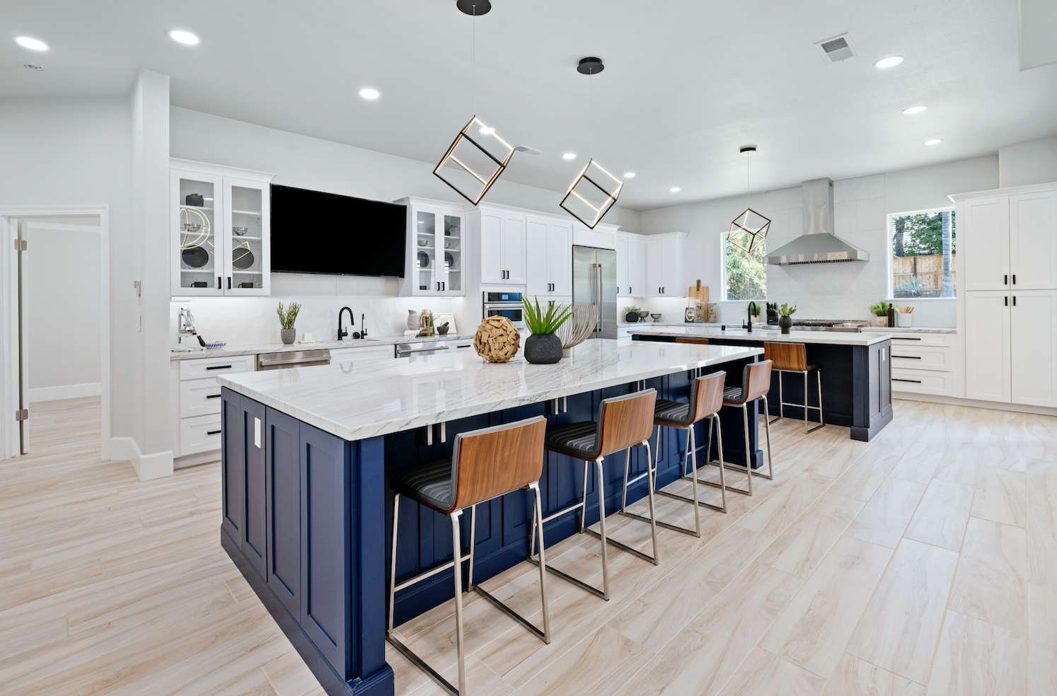 White shaker kitchen with two large blue islands and modern square chandeliers