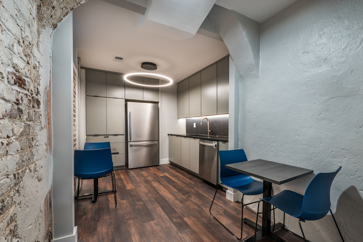 Gray slab door kitchen cabinets in Contemporary kitchen with black finger pulls, black marble slab backsplash and exposed brick in kitchen