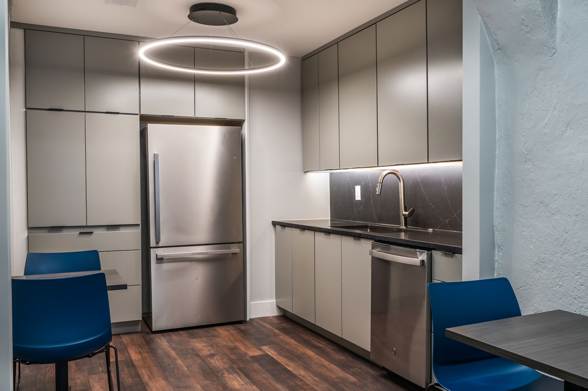 Gray slab door kitchen cabinets in Contemporary kitchen with black finger pulls, black marble slab backsplash and exposed brick in kitchen