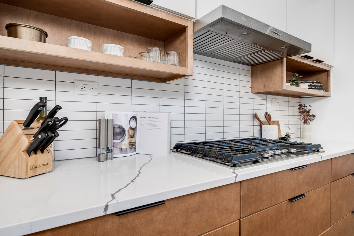 Mid-century modern kitchen design with white slab cabinets along one wall with warm wood base cabinets and accents plus a warm wood kitchen island and white quartz countertops