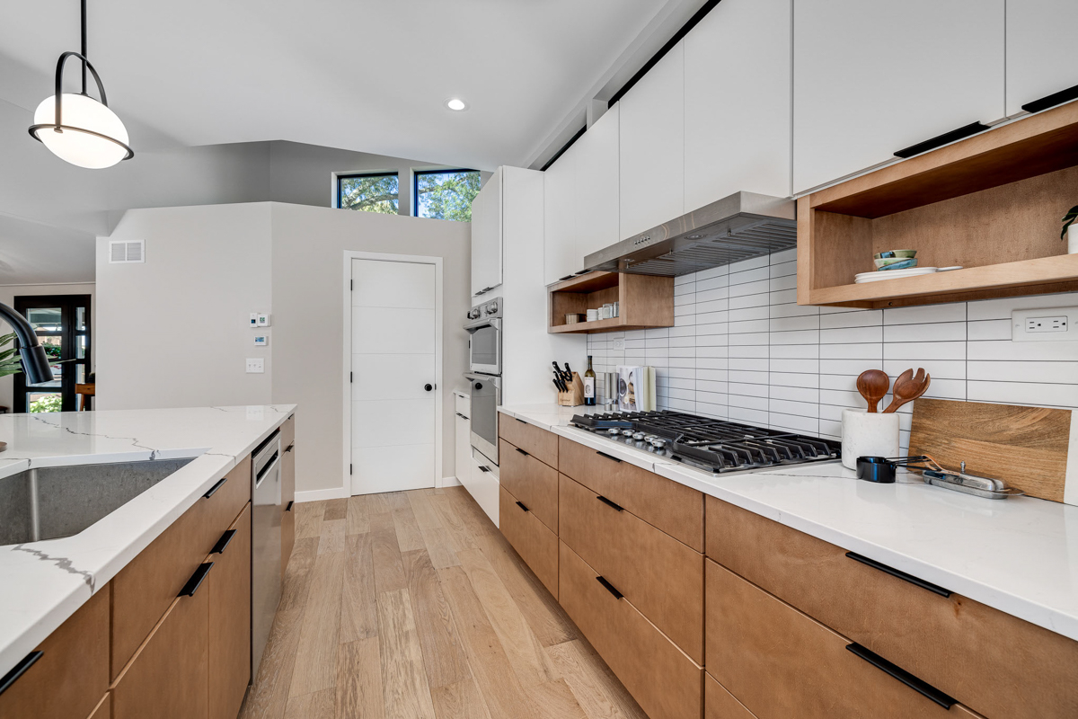 Mid-century modern kitchen design with white slab cabinets along one wall with warm wood base cabinets and accents plus a warm wood kitchen island and white quartz countertops