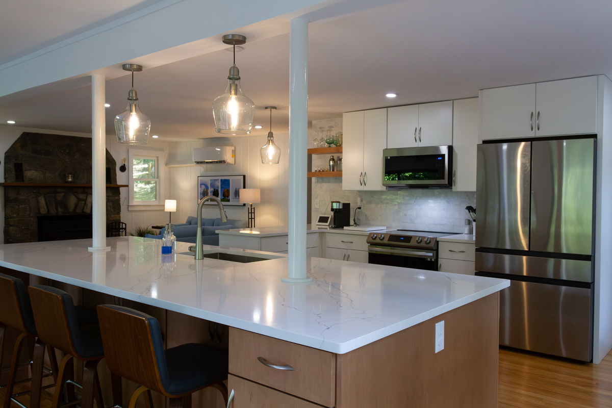 White slab door kitchen design with a warm wood island and glass pendant lights