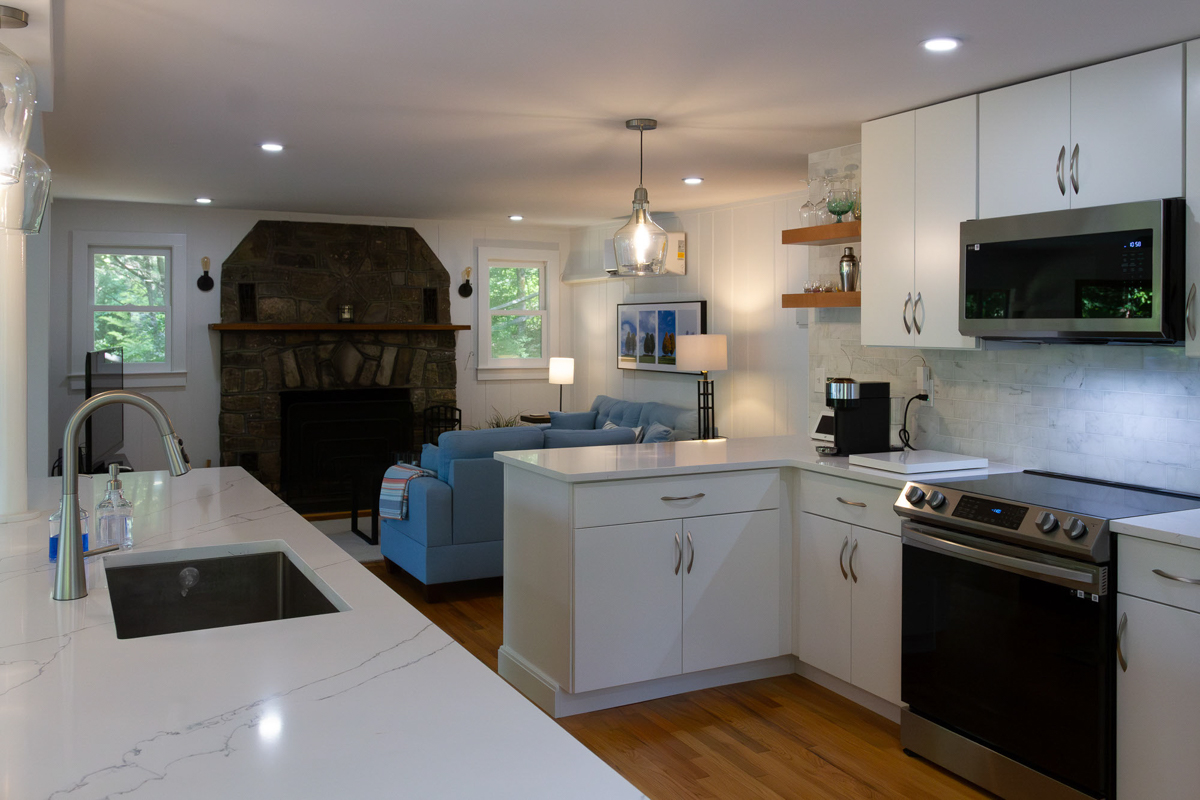 White slab door kitchen design with a warm wood island and glass pendant lights