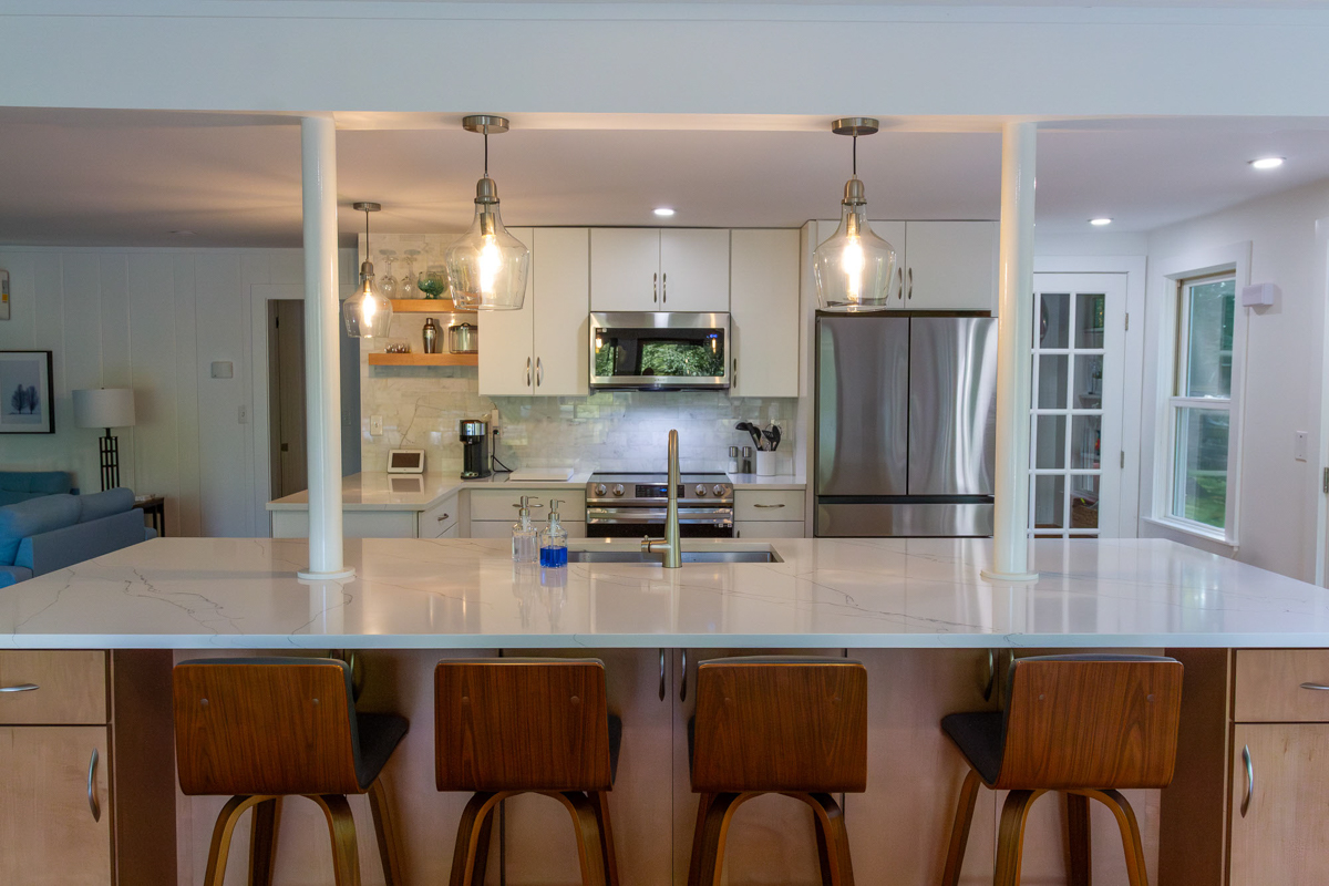 White slab door kitchen design with a warm wood island and glass pendant lights