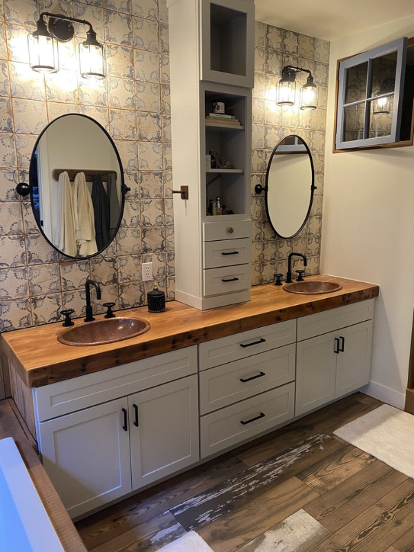 Farmhouse double vanity with soft gray shaker bathroom cabinets, a butcher block countertop, and tall wall cabinet in the center