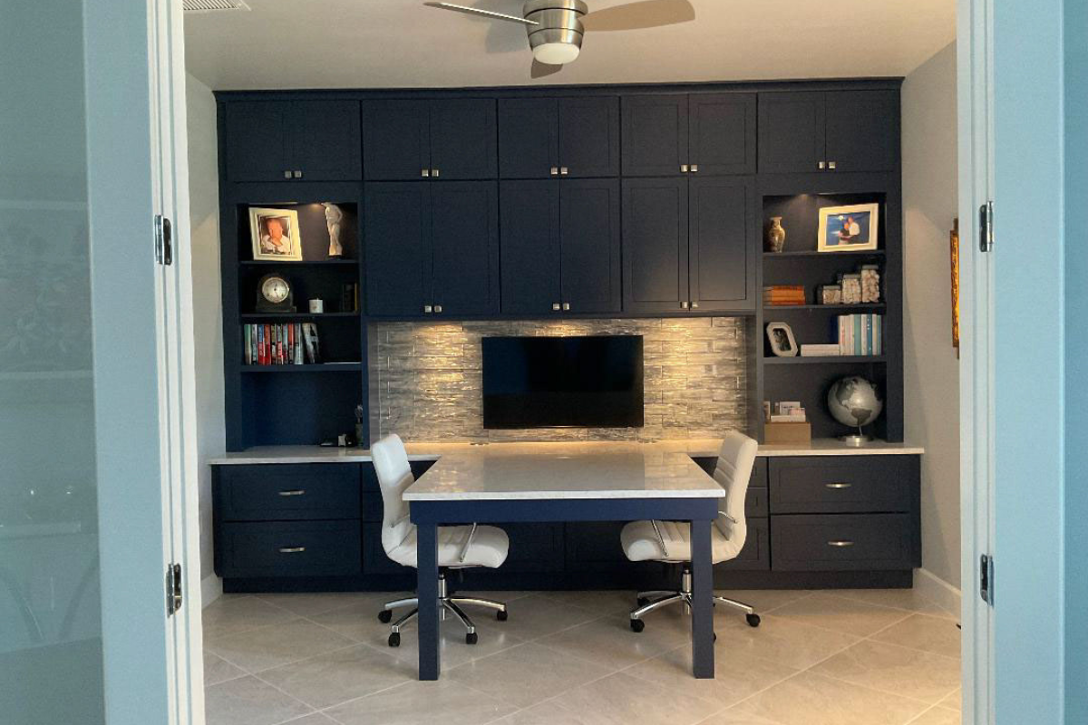 Built-in stacked navy blue office cabinetry with a peninsula countertop and chairs on either side