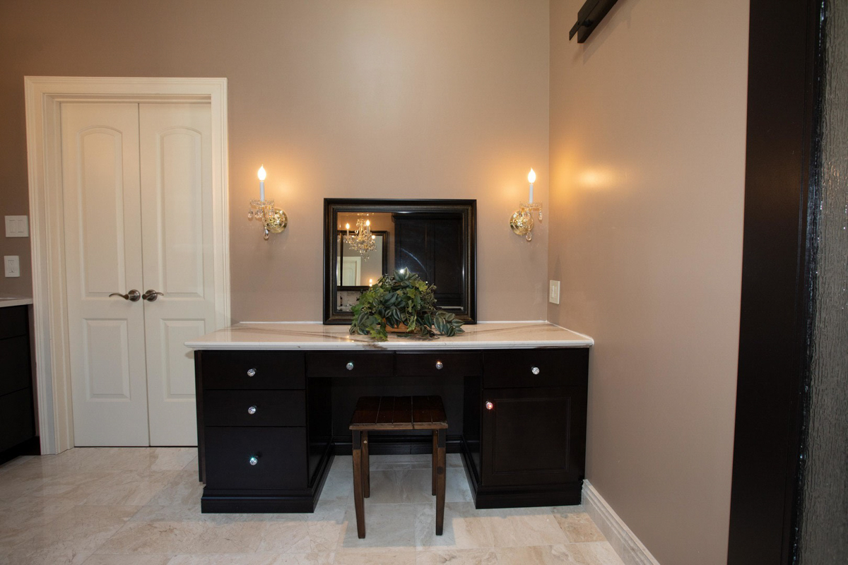 Large espresso colored decorative makeup vanity cabinet with light cream stone countertops