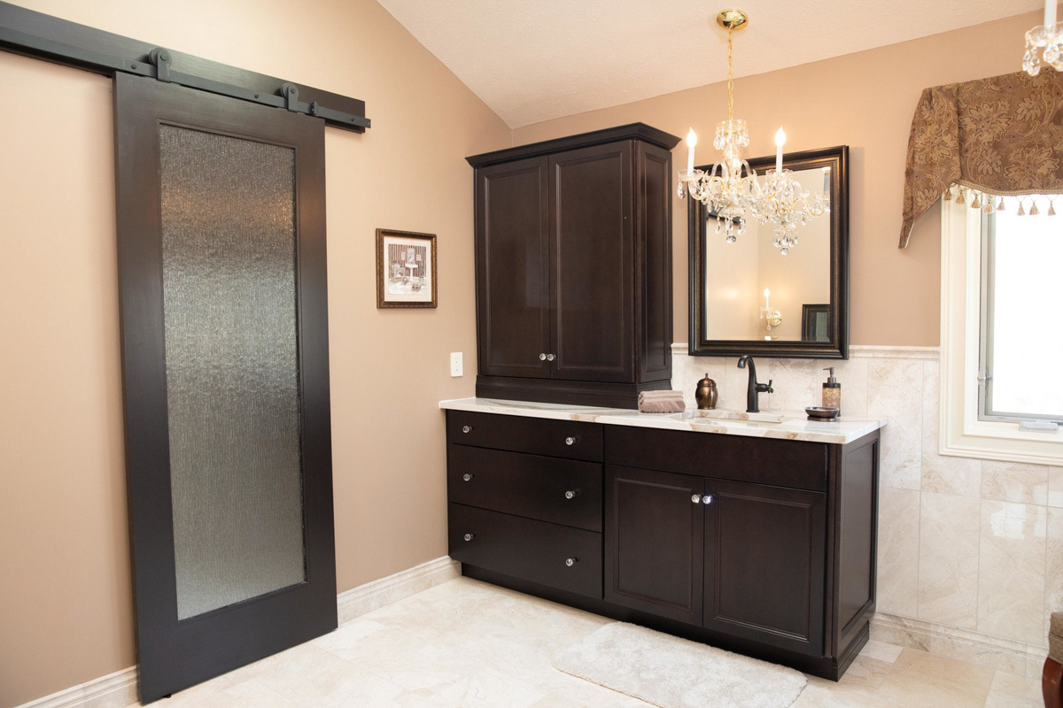 Large espresso colored decorative vanity cabinet with stacked wall cabinets on the left for storage