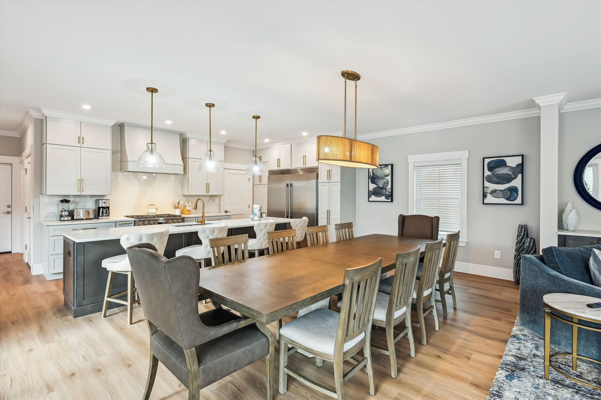 Large light gray shaker kitchen with matching wood hood, stacked cabinets with crown molding and a dark brown stained kitchen island