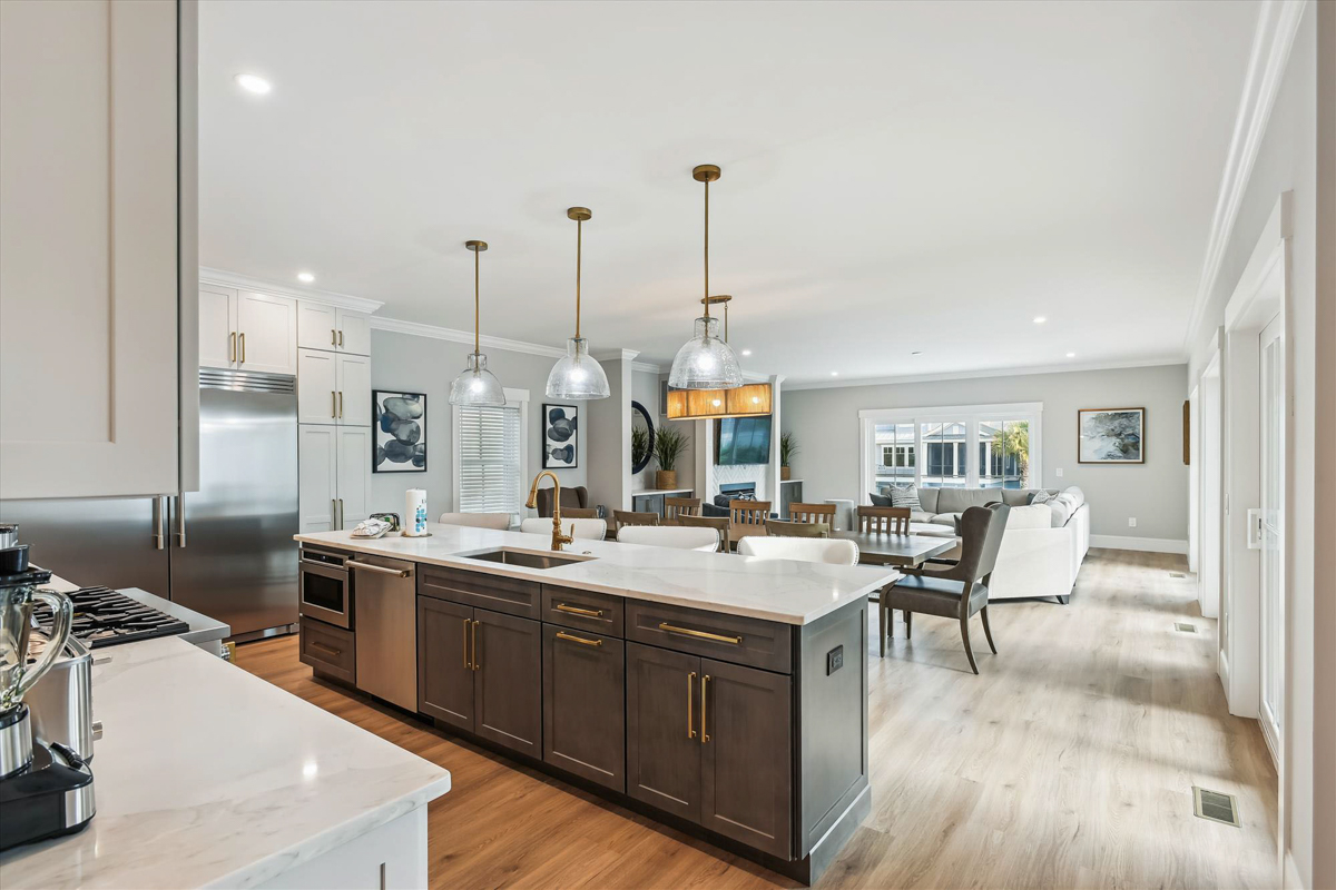 Large light gray shaker kitchen with matching wood hood, stacked cabinets with crown molding and a dark brown stained kitchen island