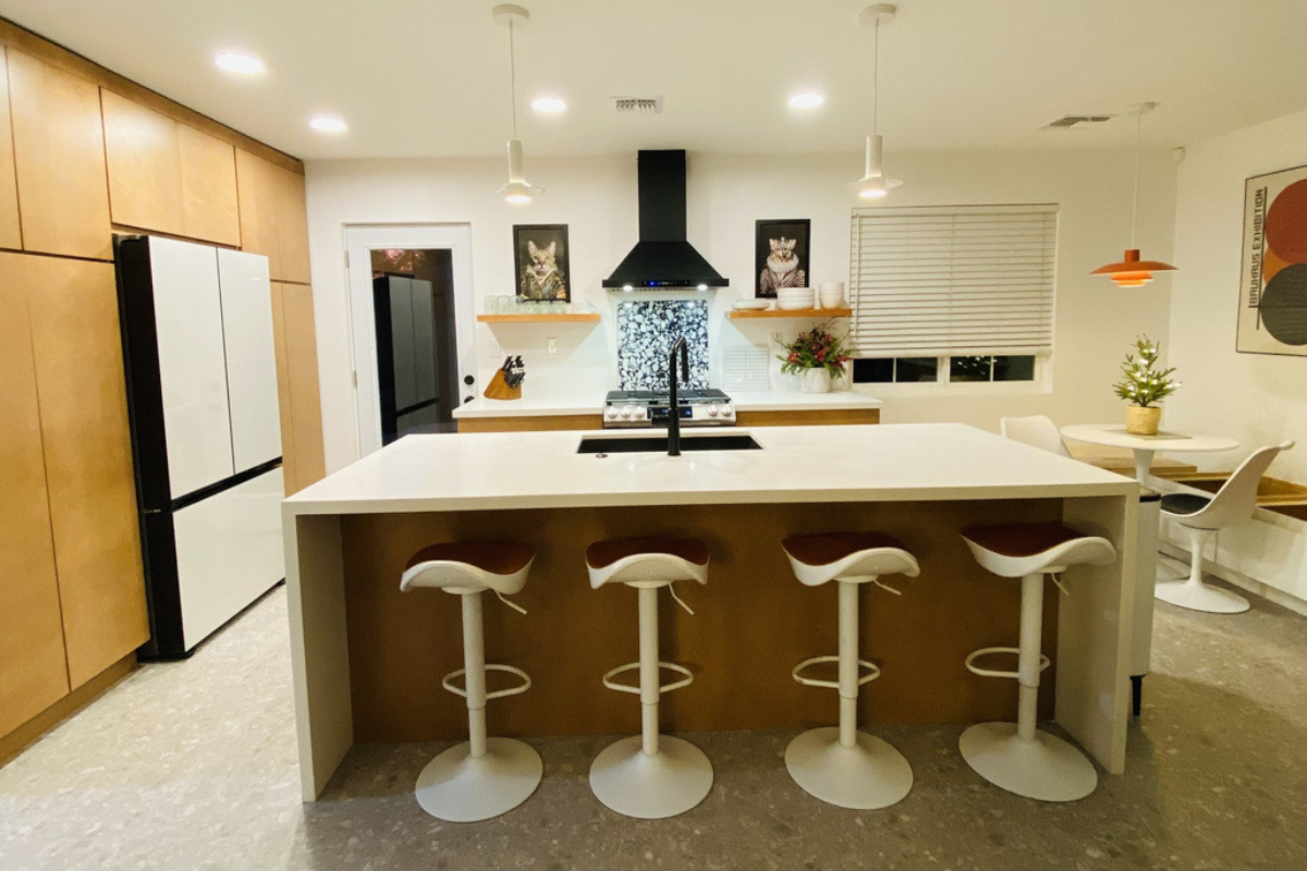 Mid-century modern kitchen design with light brown slab kitchen cabinets and a cream-colored waterfall quartz countertop