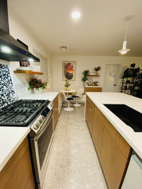 Mid-century modern kitchen design with light brown slab kitchen cabinets and a cream-colored waterfall quartz countertop