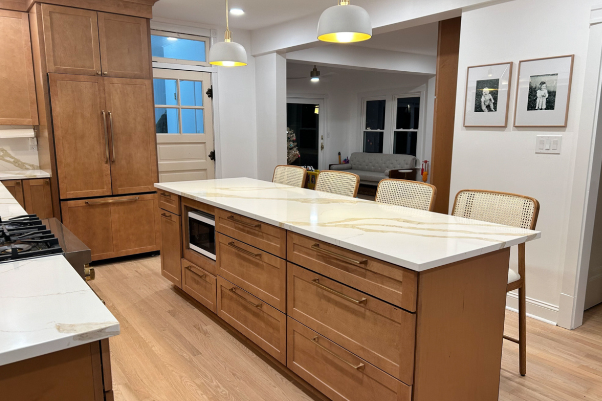 Mid-tone brown shaker kitchen island with all drawers and white quartz countertop with large tan veining.