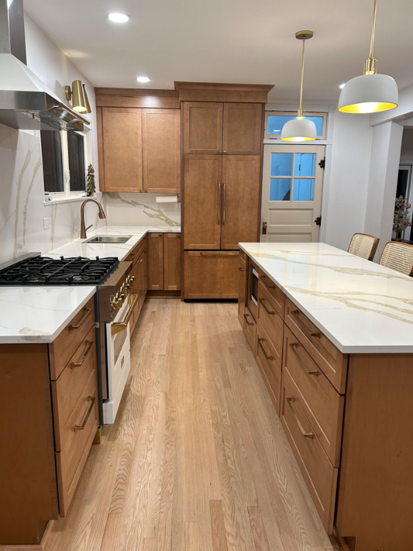 Shaker kitchen design with stained brown cabinets, a paneled refrigerator and large island full of drawers.