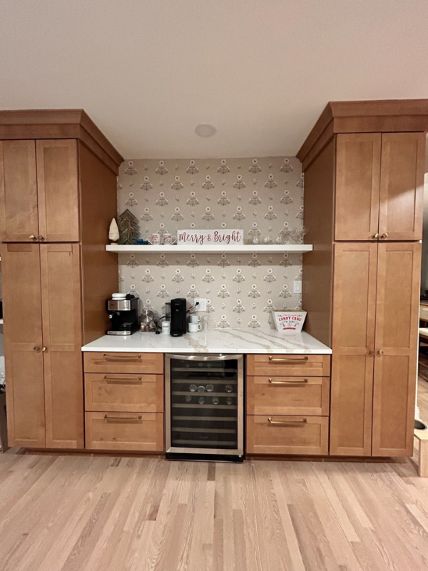 Custom shaker buffet cabinets in medium stained wood with a beverage cooler and floating shelf in the center.