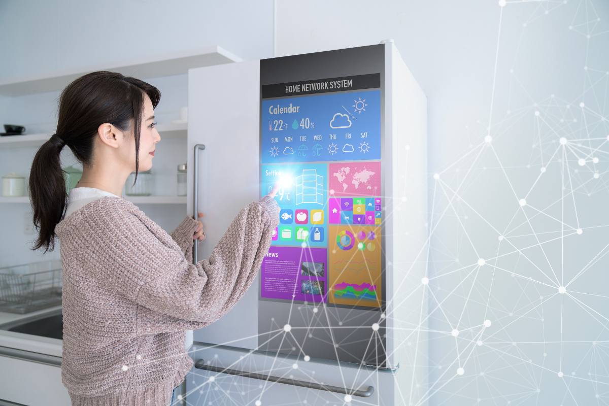 Woman touching white smart refrigerator with large control screen 