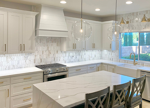 White shaker kitchen with marble countertops and glass pendant lighting